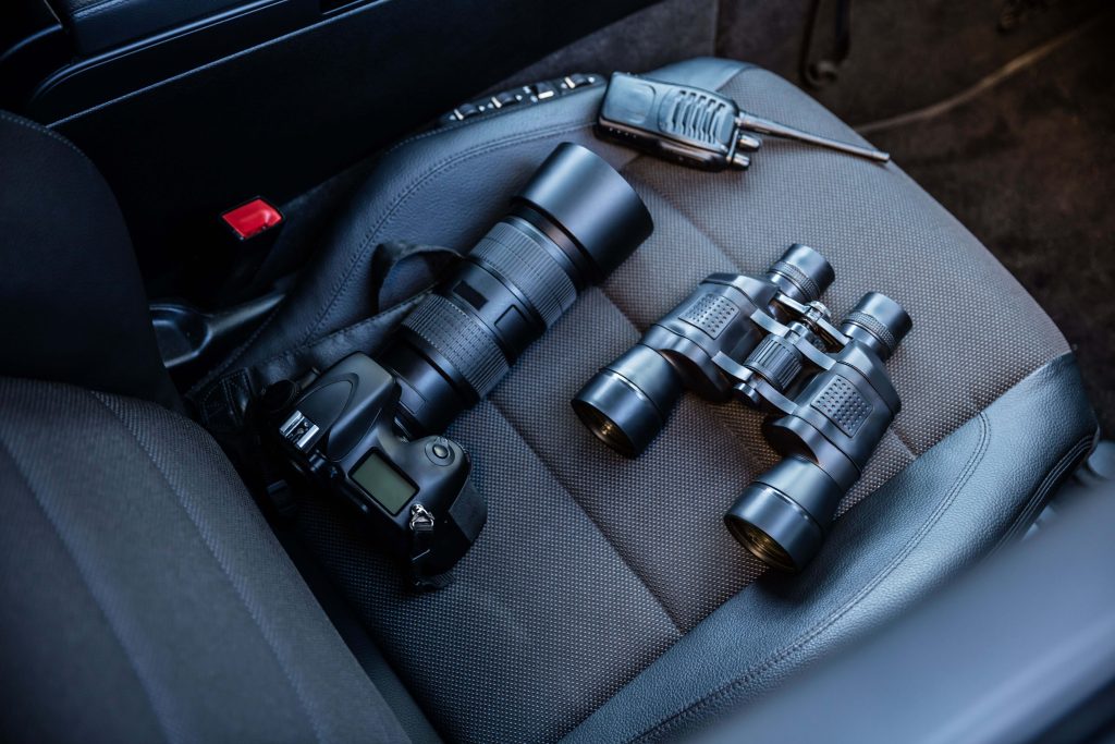 Tools used for Private investigations. Camera, Binoculars and Radio on car seat.